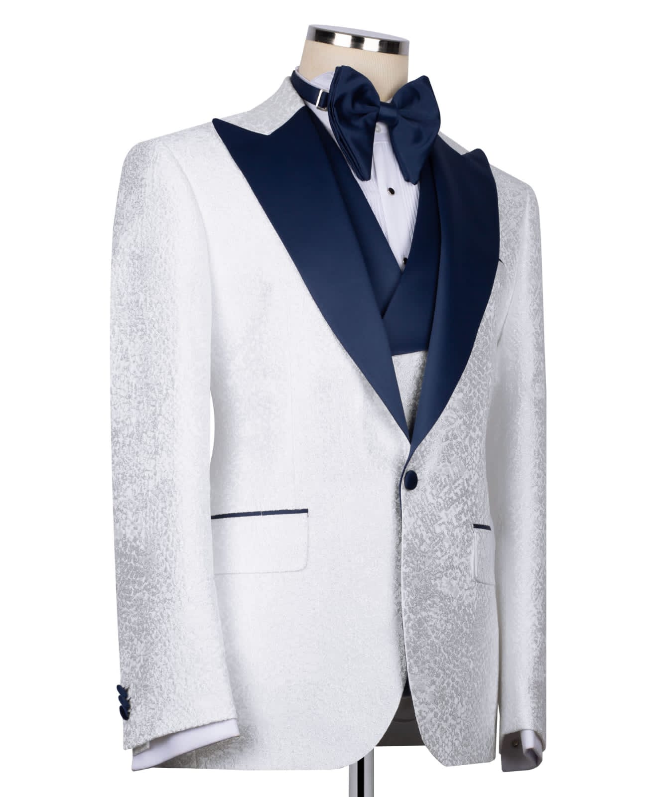 KOSS ATELIER white textured tuxedo for men with navy satin shawl lapel and matching bow tie on mannequin