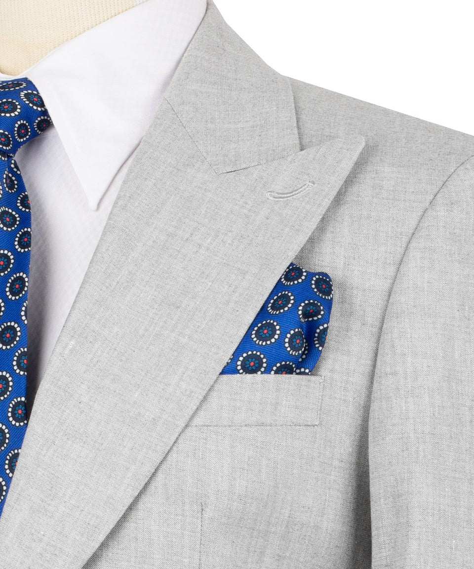 Gray suit with blue patterned tie and pocket square on a white background
