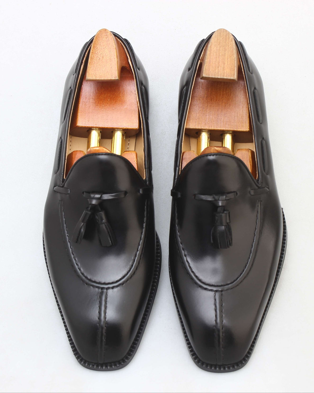 KOSS ATELIER black leather tassel loafers with a polished finish and wooden shoe trees