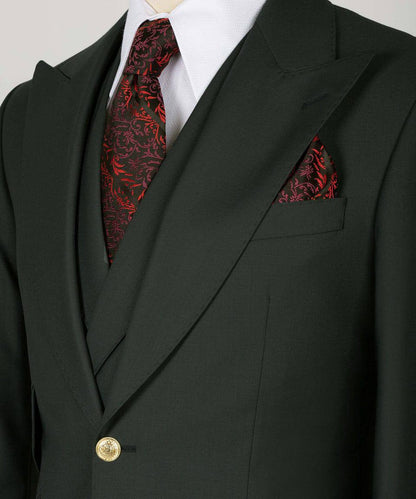 KOSS ATELIER deep green three piece suit with peak lapels gold button red patterned tie and pocket square
